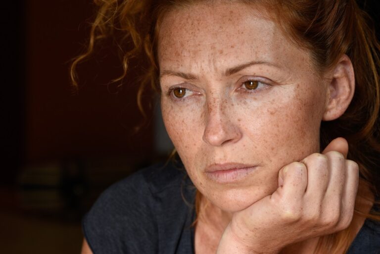 A woman with red hair and freckles looking sad.